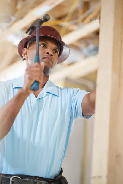 männliche architekt schlagen nagel und hammer auf holz im haus - minority african ethnicity business hardhat stock-fotos und bilder