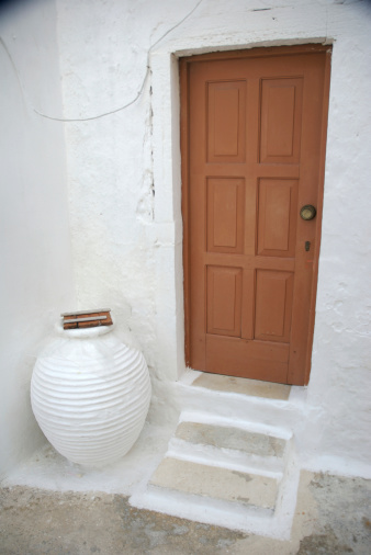 Traditional Greek front door with water jar in front of a villa are symbols of the country's culture of warm hospitality