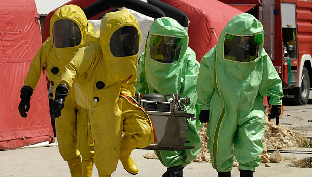 Four decontamination operatives at work in green and yellow chemical workers biochemical weapon photos stock pictures, royalty-free photos & images