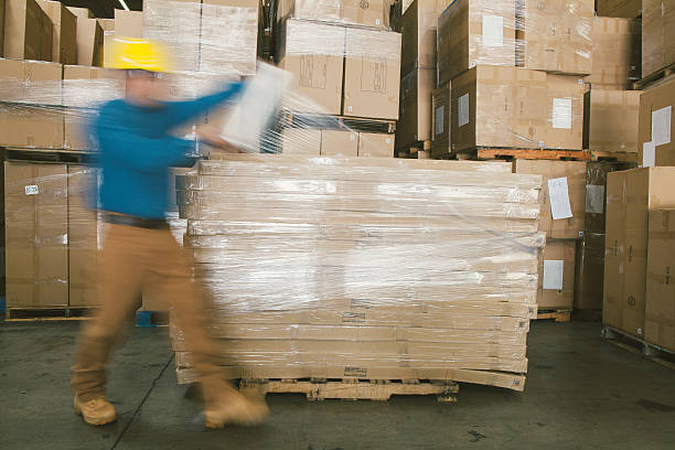 warehouse worker wrapping boxes stock photo