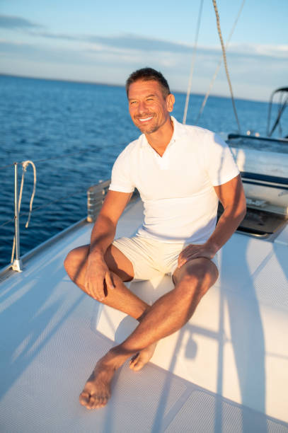 istock Man in white tshirt sitting on a yacht with a rope in hands 1724017273