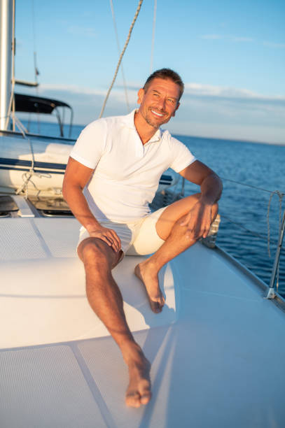 istock Man in white tshirt sitting on a yacht with a rope in hands 1724017276