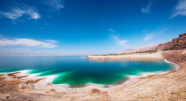 A beach by the Dead Sea with blue skies and turquoise water Dead Sea scenics in Israel and Jordan dead sea stock pictures, royalty-free photos & images