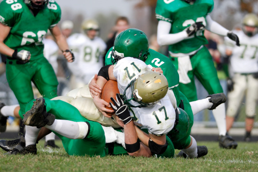 Running back is tackled during a American High School football game.