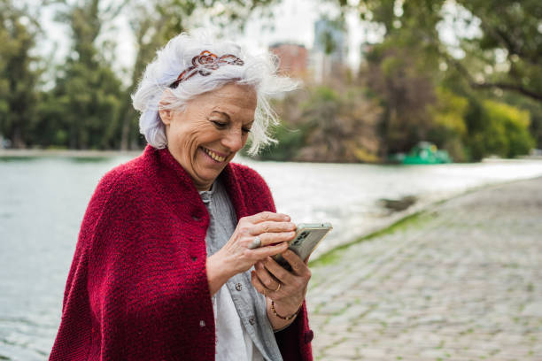 Senior woman using mobile phone on the public park