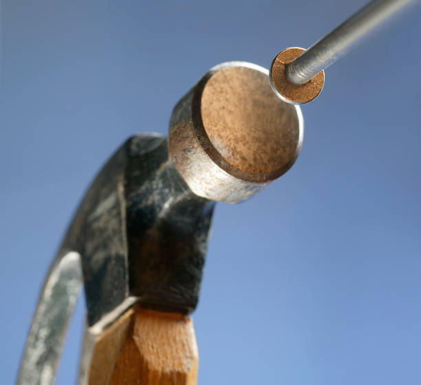 Hammer and Nail Close up of hammer pounding in nail. Blue sky background hit the nail on the head stock pictures, royalty-free photos & images