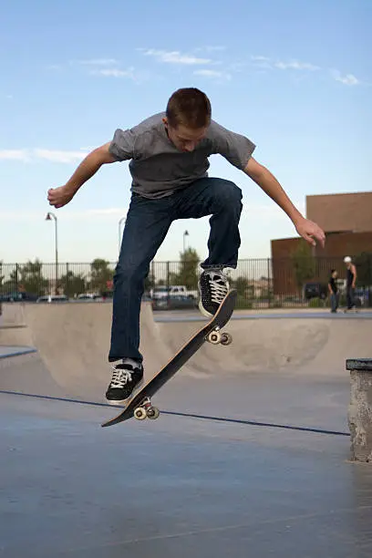 Young boy flipping skateboard at skatepark
