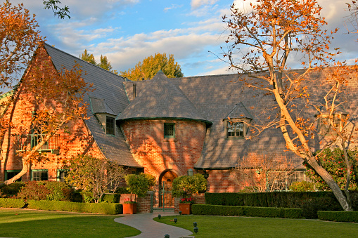 Brick tudor house looks like an autumn mansion amid trees loosing their leaves in Beverly Hills, CA