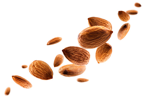 Perfectly retouched almonds fly in space forming the shape of a chain. Volumetric back light. Isolated on white.