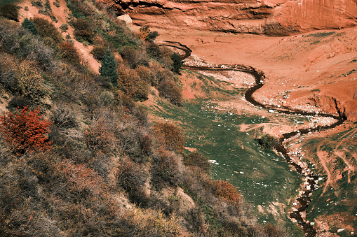 Curved river flowing between red rocks in autumn