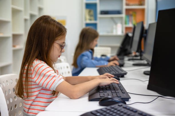 istock Little girl working on computer in school library. 1724057301