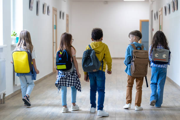 istock Back view of group of elementary school kids standing in school corridor. 1724057855