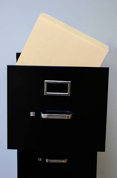 File cabinet with a manila folder sticking out stock photo