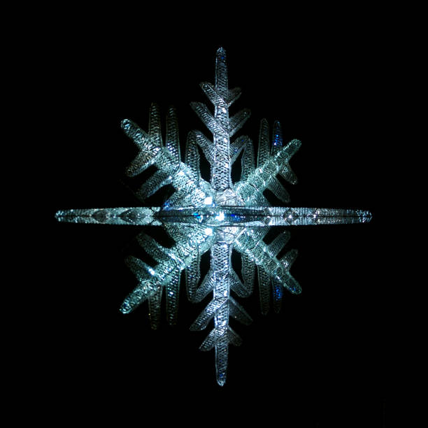 Bejeweled holiday ornament snowflake sparkling in the night sky black background
