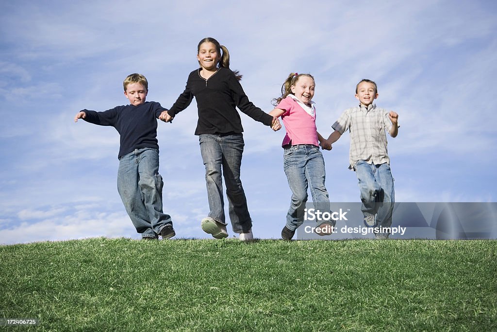 Come Play With Us! Children running on a grassy hill. Green grass and blue sky. Active Lifestyle Stock Photo