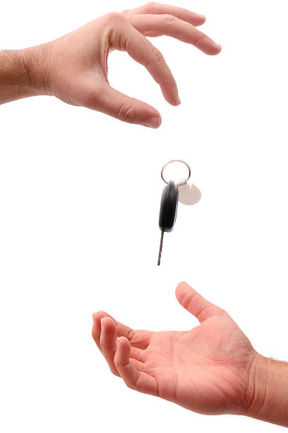 Hands with keys Car keys falling into other mans hand. Buying or borrowing a car. Isolated on white. borrowing stock pictures, royalty-free photos & images