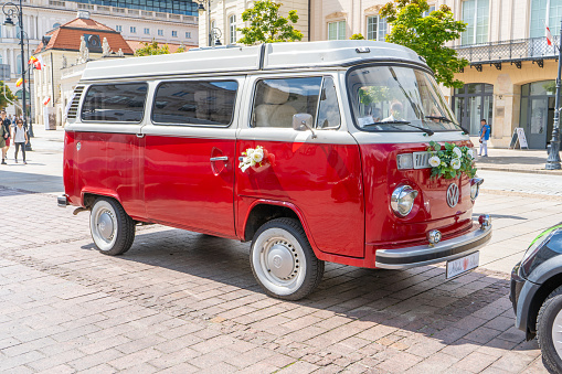 Newlyweds car. Red minibus volkswagen. Retro bus car. Decorated with bouquets of flowers. Festive decor, bridal bouquet. Just married. Poland, Warsaw - July 27, 2023.