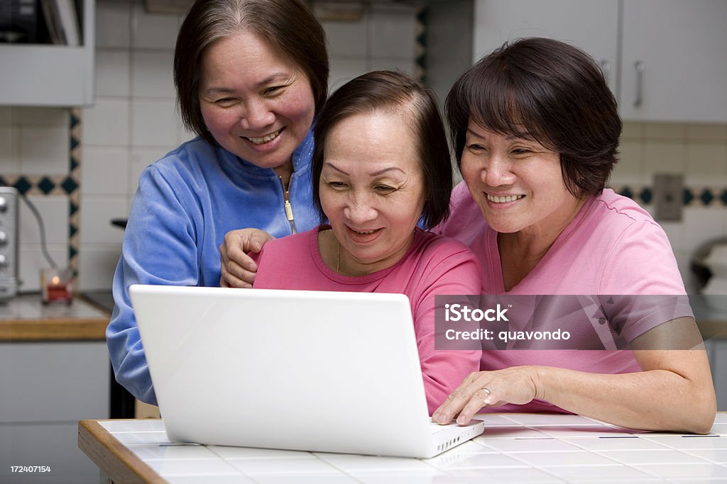 Asian Senior Adult Women Using Laptop in Kitchen, Copy Space Three older Asian sisters using a laptop in the kitchen. CLICK FOR SIMILAR IMAGES AND LIGHTBOXES WITH MORE PEOPLE USING LAPTOPS OR MORE ETHNIC FACES. Mature Adult Stock Photo