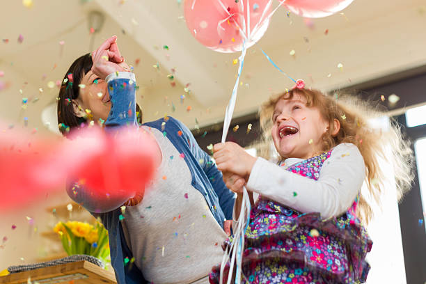 happy birthday child girl in blue dress and party hat dancing on yellow background