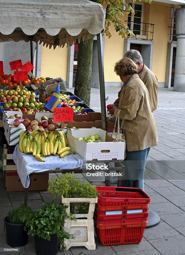 Mature couple buying apples at farmers market "A couple buying fruit at farmers market in Stockholm, Sweden.The signs tell the type of fruit and the price in Sw.cr. and the fleag indicates that at least some of the fruit is Swedish grown. See also my lightbox:" 60-69 Years Stock Photo