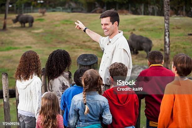 Guarda Do Jardim Zoológico Com Grupo De Crianças Na Rhino Apresentar - Fotografias de stock e mais imagens de Jardim Zoológico