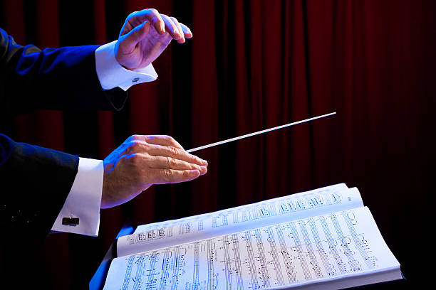 Close-up of a conductors hands conducting music Conductor's hands with a baton and music score conductors baton photos stock pictures, royalty-free photos & images