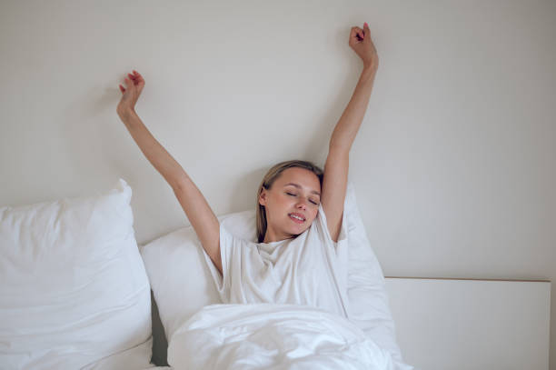 istock Young smiling girl waking up and stretching in bed 1724101051