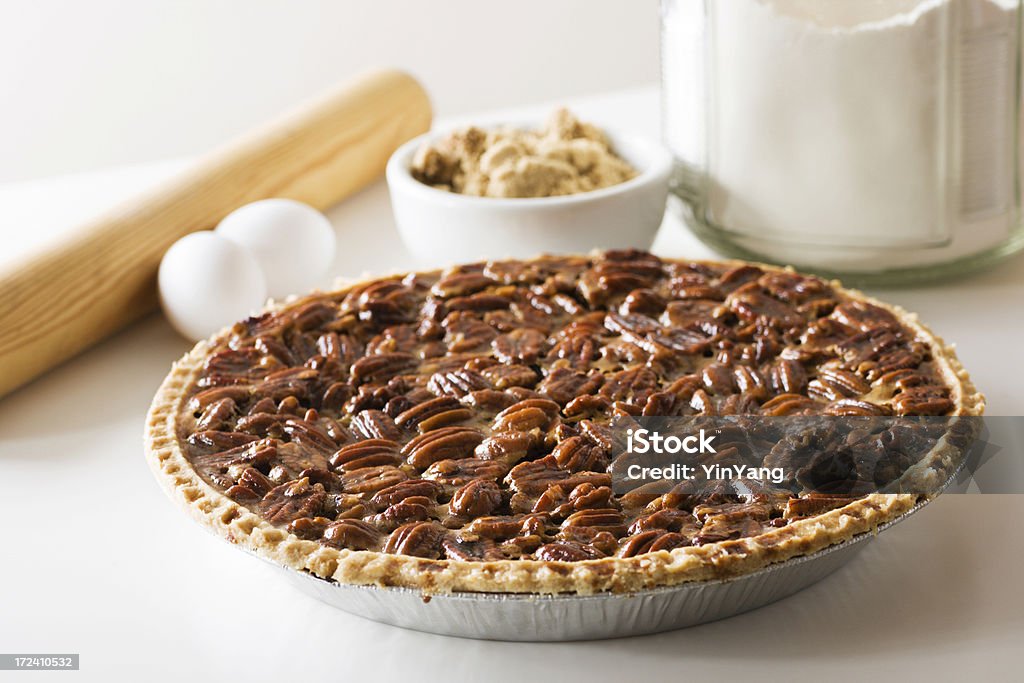 Pecan Pie, Fresh Baked Holiday Dessert with Ingredients, Rolling Pin A freshly baked pecan pie with ingredients and a rolling pin in the background. The delicious homemade dessert is ready for a holiday or other special occasion. Pecan Pie Stock Photo