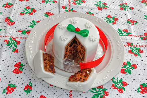 Two slices of delicious fruit Christmas cake with white frosting on a white plate
