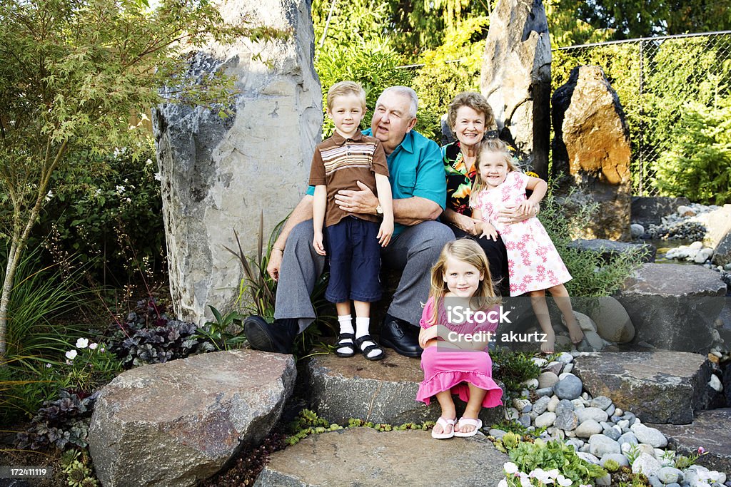 Grandparents and grand children Grandma and Grandpa with three grandchildren outside sitting on huge  House Stock Photo