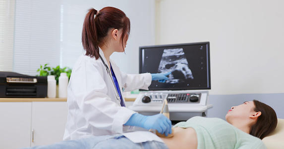 asian doctor using ultrasound scanner performing examination of  belly for her patient - feminine health medical concept