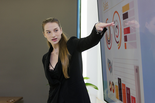 Caucasian woman present a financial graph on the board in meeting room