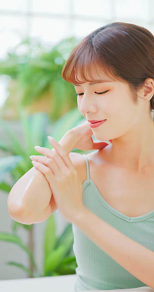 skin care concept - asian confident woman is applying lotion and moisturizer on her elbows