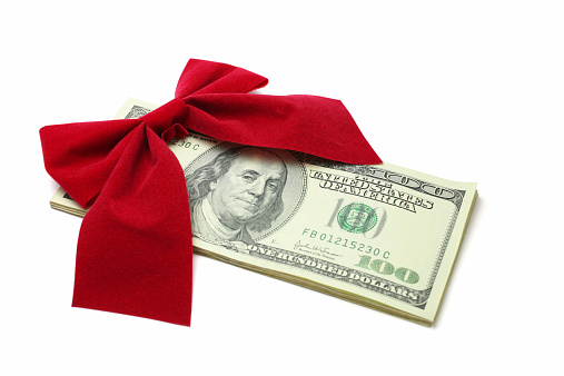 Red bow on a stack of one hundred dollar bills. Isolated white background.