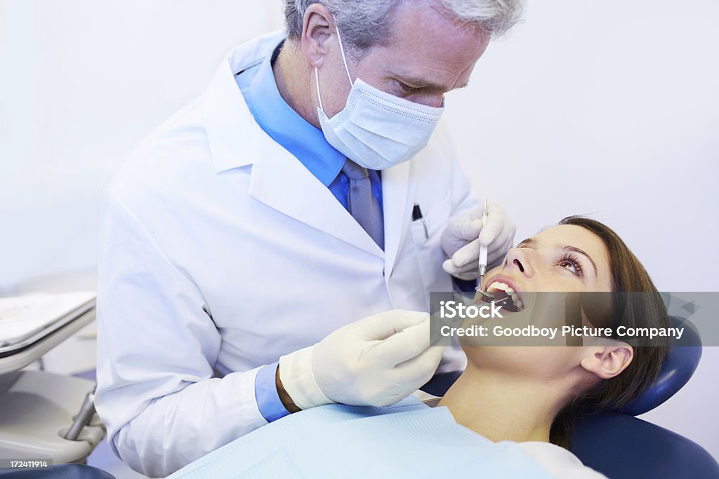 These teeth are perfectly healthy A mature dentist examining a pretty young woman's teeth Adult Stock Photo