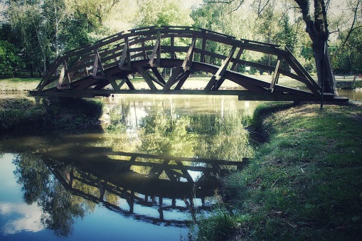 A small wooden bridge in the park over the pond in Radzanów