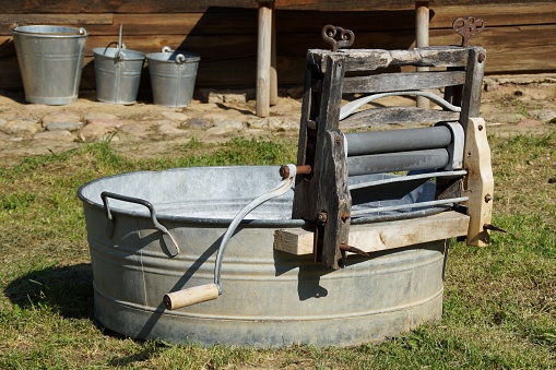 An old manual wringer mounted on a metal tub.