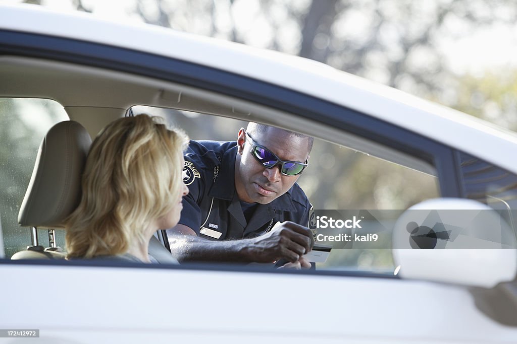 Woman pulled over by police Woman driving car, pulled over by African American police officer (20s). Driving Stock Photo