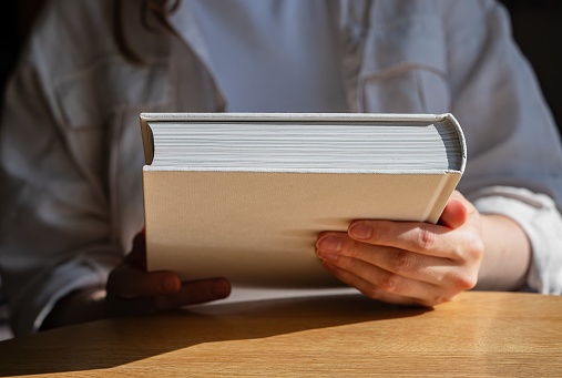 Hand holding new closed book for reading