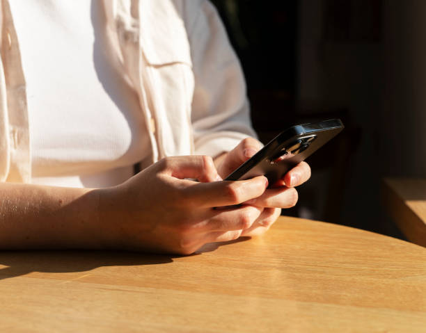 istock Hands texting, holding mobile phone at wooden table 1724135127