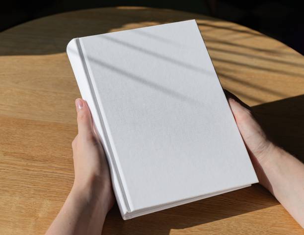 istock Hands holding book in hard cover mock up on wood table 1724135138
