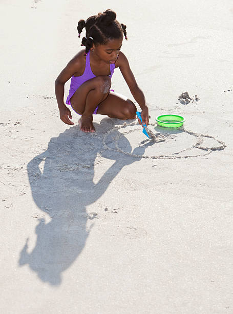 African American girl (6 years) playing with sand at the beach.