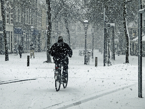 A biker dares to ride his bike on the fresh snow.