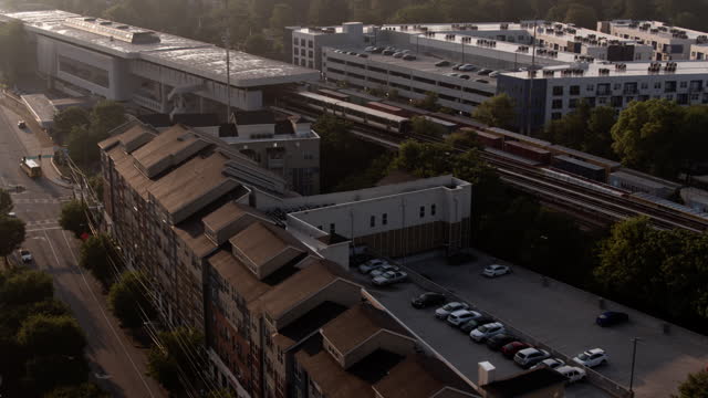 Rail service to Downtown in the morning. Deserted suburban row houses and parking among the railroad of Atlanta, GA. Aerial footage with forward-panning-ascending camera motion