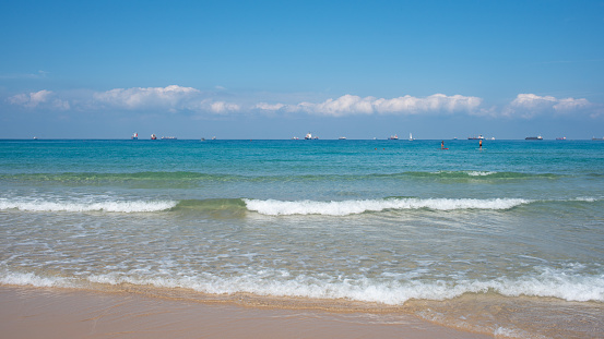 Sand beach, turquoise sea and cloudy blue sky. Summer travel background