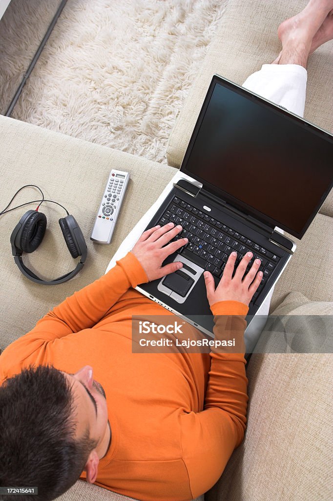 A man working at home in a laptop with headphones and remote Young man working at home. Laptop Stock Photo