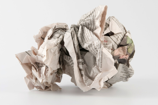 Toss in the trash with a red background. A crumpled ball of paper is tossed into a wicker waste paper basket with a red background.  Shadow of crumpled paper ball shown with lots of room for copy space. Conceptual image for tossing away.
