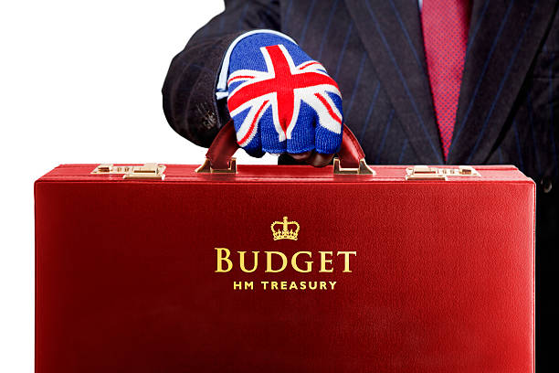 Budget for UK Treasury The Chancellor of the Exchequer presents the UK fiscal Budget, contained within the traditional red briefcase. Good copy space. Isolated on white. The United Kingdom Budget statement is made by the Chancellor of the Exchequer, a member of the Government  who is responsible for all economic and financial matters. He controls and is responsible for HM Treasury and the revenues gathered by Her Majesty's Revenue and Customs and the expenditure of public sector departments. He raises and lowers taxes and duties according to the needs of the economy. After the Prime Minister he is the most important state officer. The Budget is normally an annual event in March, but in more recent times a mini budget has also been held in November. The budget speech is always carried to the House of Commons in a red briefcase, known as Ministerial Boxes, or Red Boxes’. This red briefcase has become representative of the annual UK Budget. Historically, it dates back to the first use by William Gladstone in 1860. houses of parliament london photos stock pictures, royalty-free photos & images