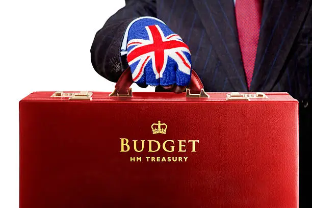 The Chancellor of the Exchequer presents the UK fiscal Budget, contained within the traditional red briefcase. Good copy space. Isolated on white. The United Kingdom Budget statement is made by the Chancellor of the Exchequer, a member of the Government  who is responsible for all economic and financial matters. He controls and is responsible for HM Treasury and the revenues gathered by Her Majesty's Revenue and Customs and the expenditure of public sector departments. He raises and lowers taxes and duties according to the needs of the economy. After the Prime Minister he is the most important state officer. The Budget is normally an annual event in March, but in more recent times a mini budget has also been held in November. The budget speech is always carried to the House of Commons in a red briefcase, known as Ministerial Boxes, or Red Boxes’. This red briefcase has become representative of the annual UK Budget. Historically, it dates back to the first use by William Gladstone in 1860.