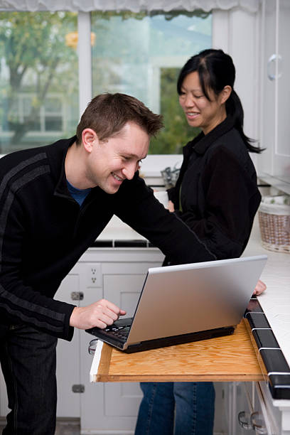 istock Cheerful Young Couple Smiling, Using Laptop in Home Kitchen, Copyspace 172416684